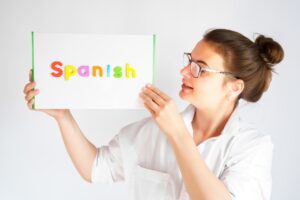 Learning Spanish educational courses. Native tutor, woman teacher in glasses with magnetic sign in